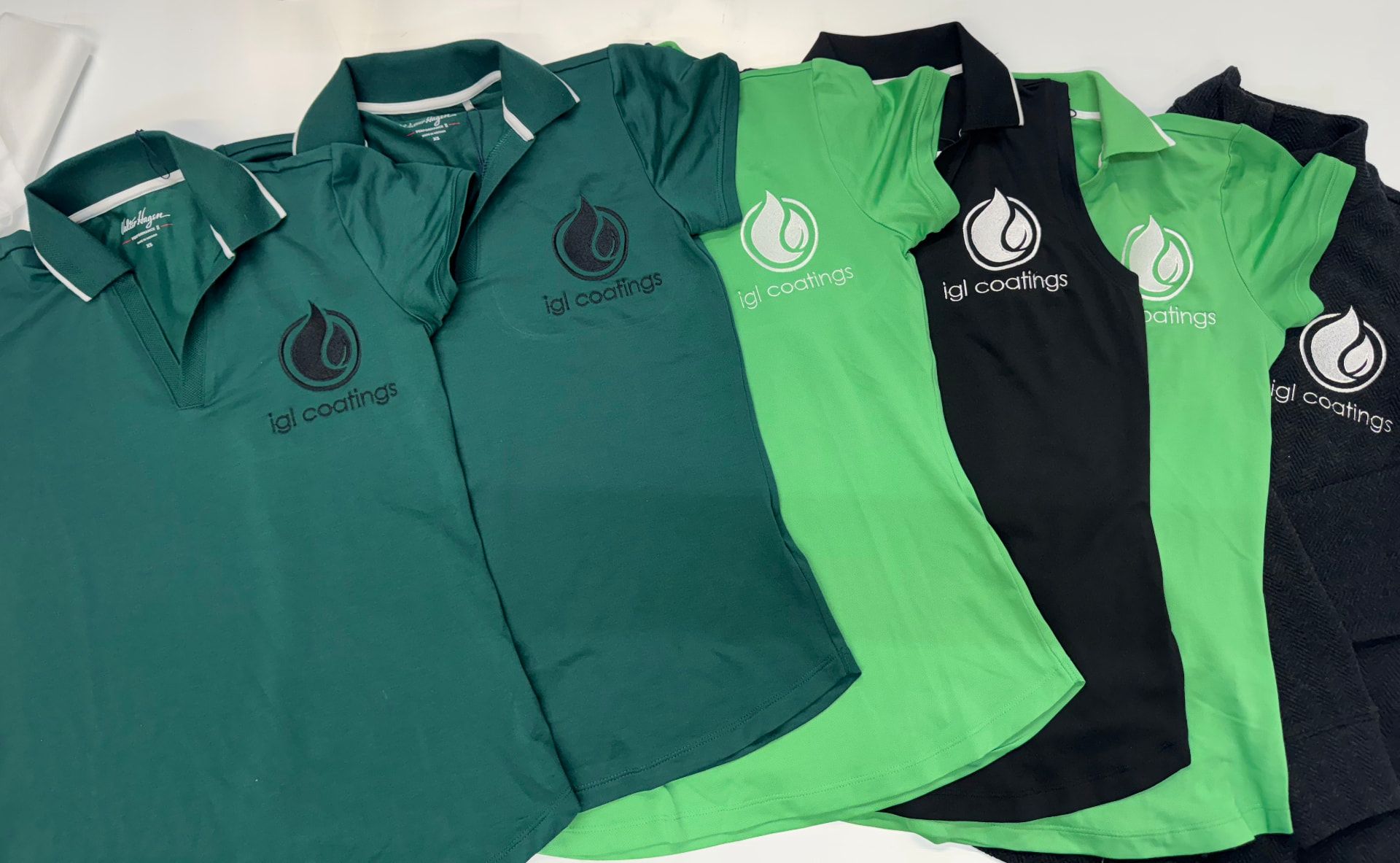 Green and black igl coatings embroidered polos folded in a row
