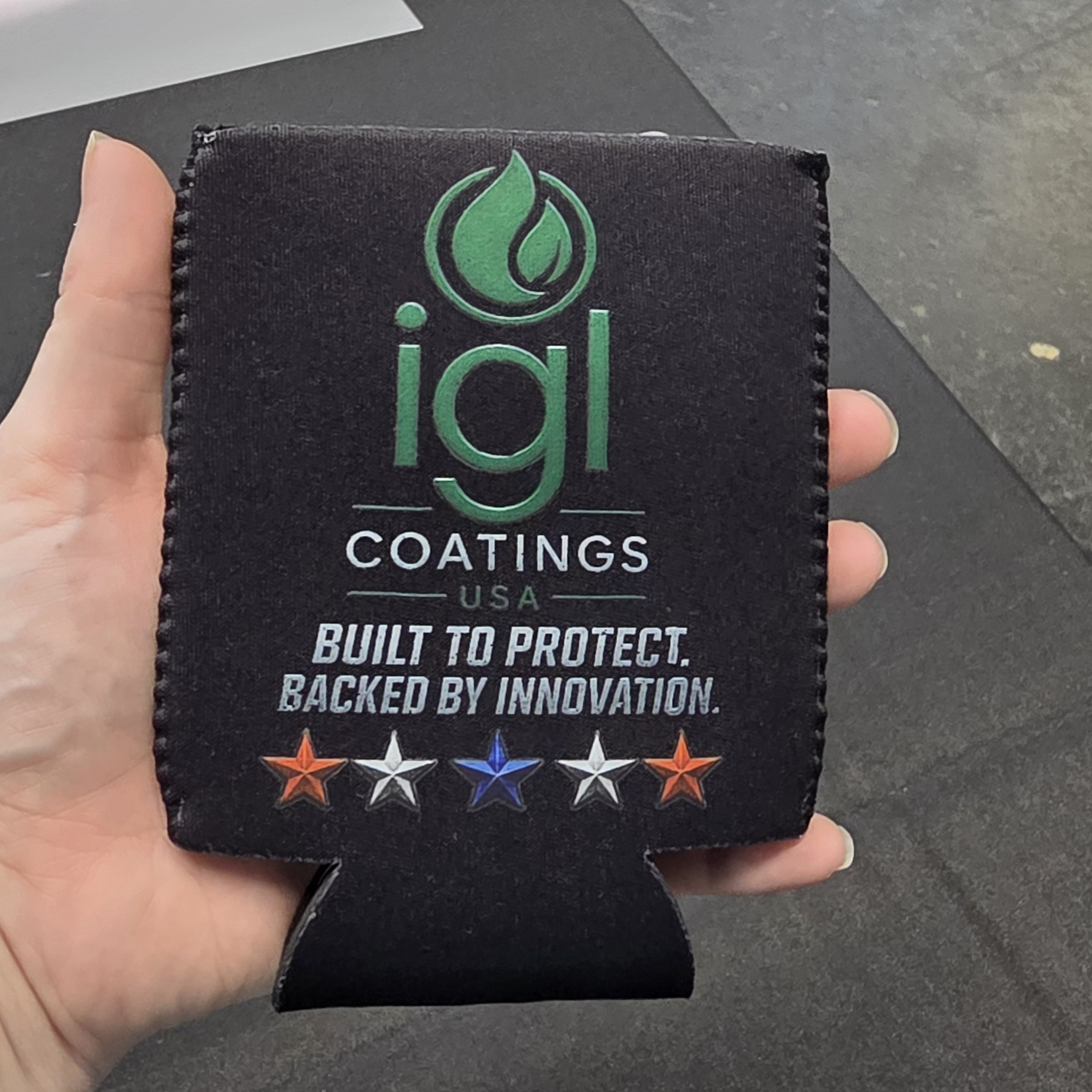 Black can koozie printed with the igl coatings USA logo and Built to Protect tagline
