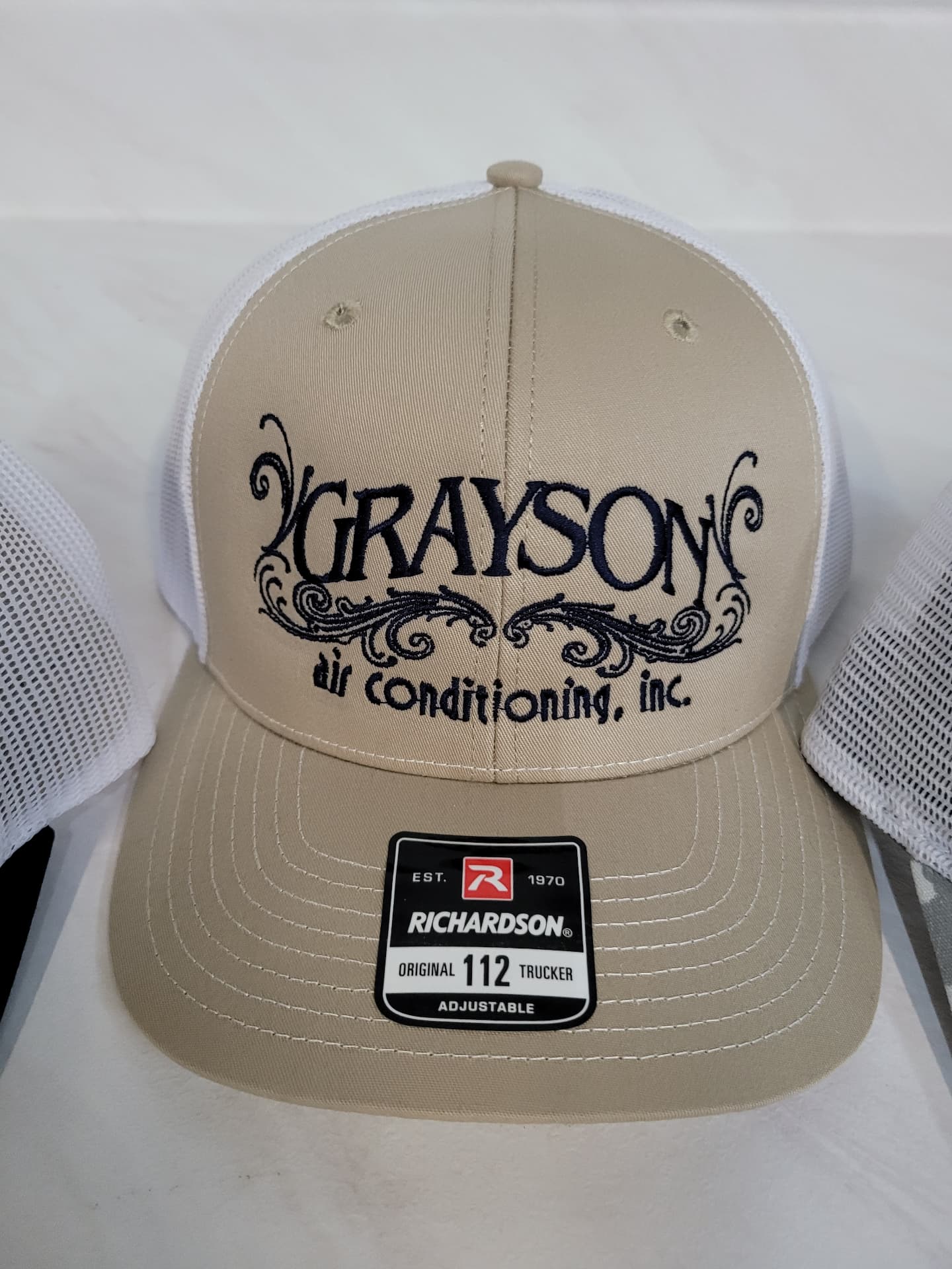 Tan and white Richardson 112 trucker hat with navy embroidered Grayson Air Conditioning logo